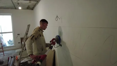 Construction worker prepares wall surface for painting in a room at a renovation 스톡 동영상 332477246