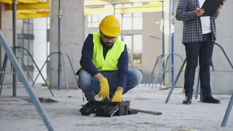 Construction worker preparing tools under supervisor's watch Stock Footage 343449595