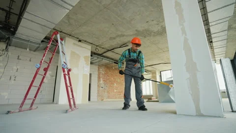 Construction worker priming walls in unfinished building Stock Footage 312838773