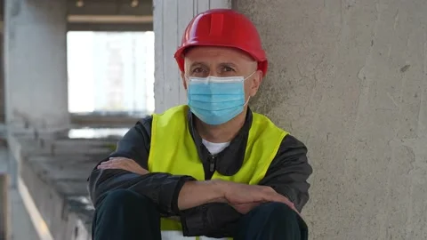 Construction worker in protective face mask sits on the floor and look at camera Stock Footage 146915694