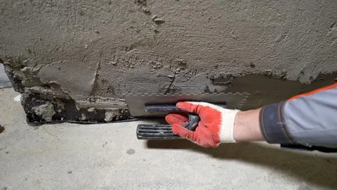 Construction worker in protective glove using notched trowel to apply fresh.. Stock Photos
