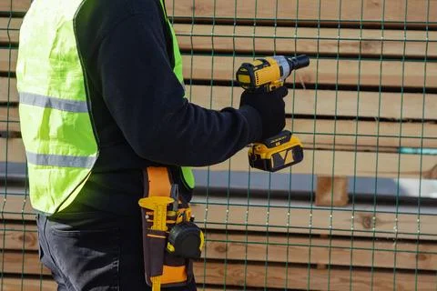 Construction worker in protective gloves and high visibility vest installin.. Stock Photos