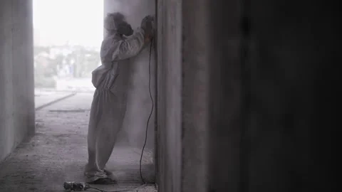 A construction worker in a protective suit polishes concrete walls Video stock 247546587