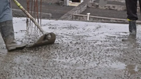 Construction worker pulling and leveling m20 grade concrete mixer on slab work Stock Footage 320397944