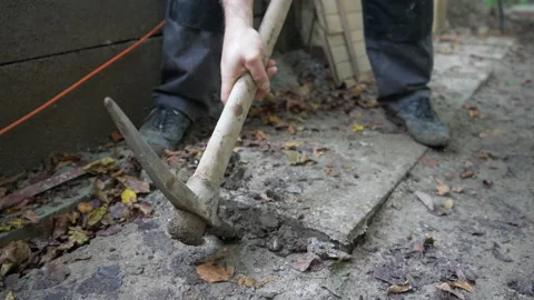 Construction worker pulling out the tile from footpath with mattock Stock Footage 158979658