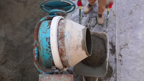Construction worker pushing wheelbarrow with concrete near cement mixer Stock-Footage 280549045