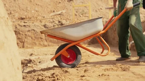 Construction worker pushing wheelbarrow filled with sand Stock Footage 341294863