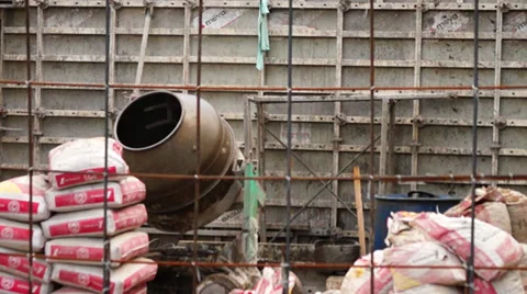 Construction Worker puts a sack of gravel in concrete mixer Stock Footage