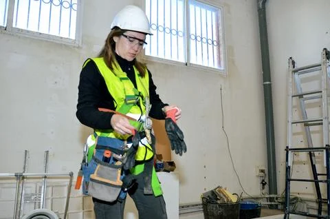 Construction worker putting on gloves in building renovation site Stock Photos