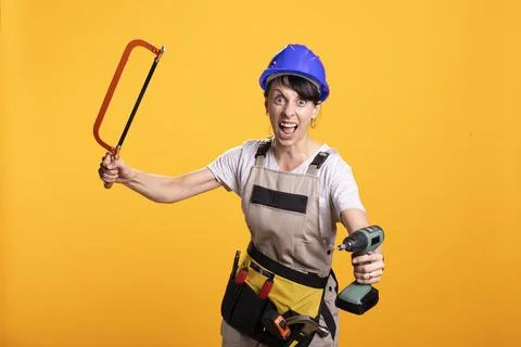 Construction worker raises drill and handsaw with energetic enthusiasm Stock Photos