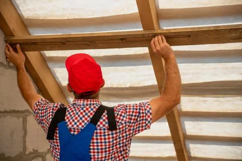 Construction worker in a red cap and work uniform carefully measures and in.. Fotos Stock