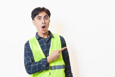Construction worker in a reflective vest pointing to the side with a funny .. Stock Photos