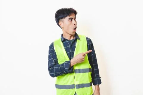 Construction worker in a reflective vest pointing to the side with a funny .. Stock Photos