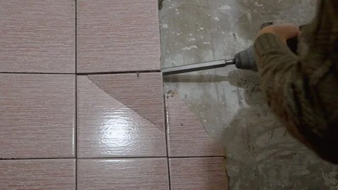 Construction worker removing floor tiles with chisel and hammer Stock Footage 297457501