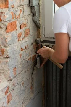 Construction worker repairing an old brick wall using a hammer and chisel Stock Photos