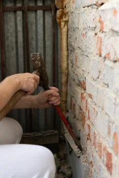 Construction worker repairing an old brick wall using a hammer and chisel Stock Photos