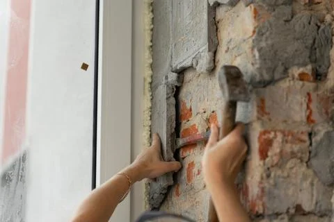 Construction worker repairing an old brick wall using a hammer and chisel Stock Photos