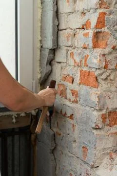 Construction worker repairing an old brick wall using a hammer and chisel Stock Photos
