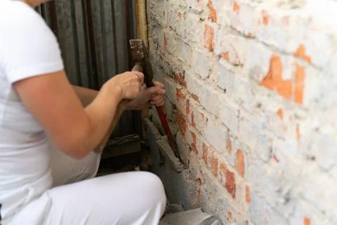 Construction worker repairing an old brick wall using a hammer and chisel Stock Photos