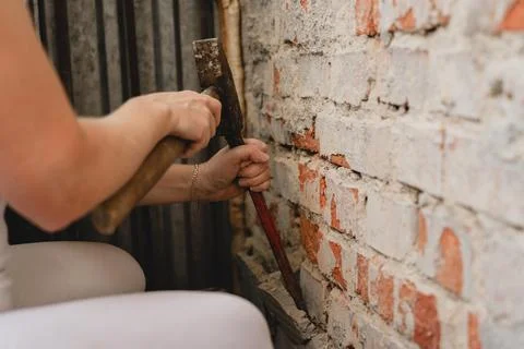 Construction worker repairing an old brick wall using a hammer and chisel Stock Photos