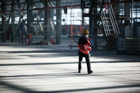 A construction worker in a robe is walking along the production workshop Stock Photos