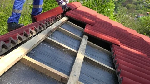 Construction worker on a roof covering it with tiles - roof renovation, roofing Stock Footage 154367481