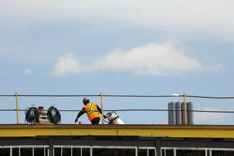 Construction worker roofer carrying propane torch and gas tank to repair fl.. Stock-Fotos