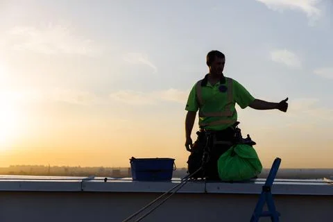 Construction Worker on Rooftop at Sunset: Celebrating Achievement with a Thumbs Stock Photos