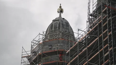 Construction worker in safety gear restoring an old building's dome surrounded Stock Footage 332114810