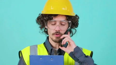 Construction worker with safety glasses and helmet that is talking on mobile Stock Footage 150829682