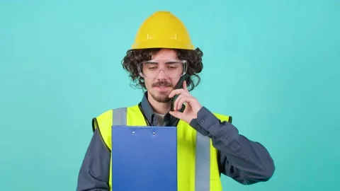 Construction worker with safety glasses and helmet that is talking on mobile Video stock 153616023