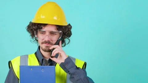 Construction worker with safety glasses and helmet that is talking on mobile Stock Footage 155761333
