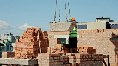 Construction worker in safety vest and helmet guiding suspended metal container Stock Footage 316543720