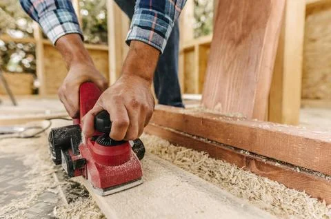 Construction worker sanding down wood piece Stock Photos