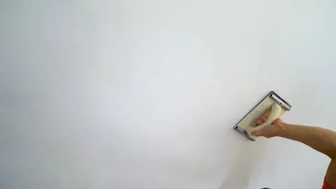 Construction worker sanding wall with hand sander during home renovation Stock Photos