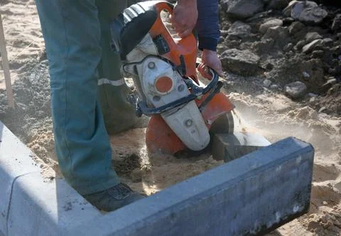 A construction worker saws a concrete block. Stock Photos