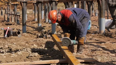 A construction worker saws a metal beam with a manual circular saw. Stock Footage 231160674