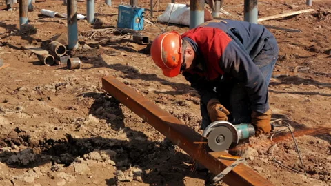 A construction worker saws a metal beam with a manual circular saw. Stock Footage 255826154