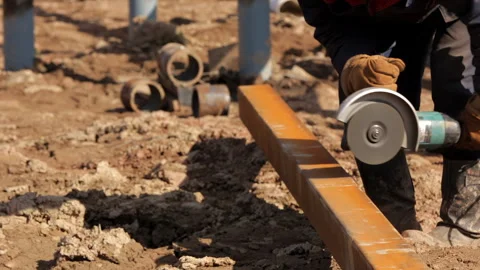 A construction worker saws a metal beam with a manual circular saw. Stock Footage 256105573