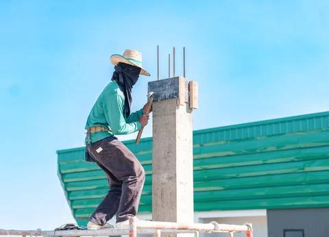 Construction worker on scaffolding using a hammer to secure wooden formwork.. Stock-Fotos