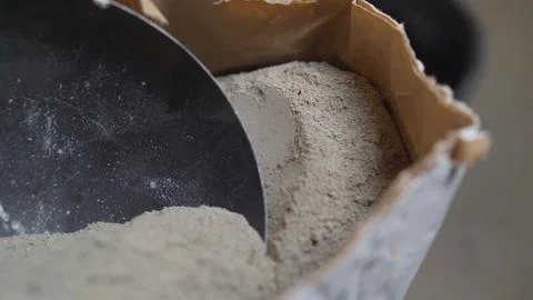 Construction worker scooping cement powder from bag with metal trowel Stock Photos