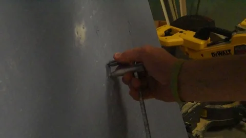Construction worker scoring hole for cutting in sheet of plasterboard Vidéo 113394567