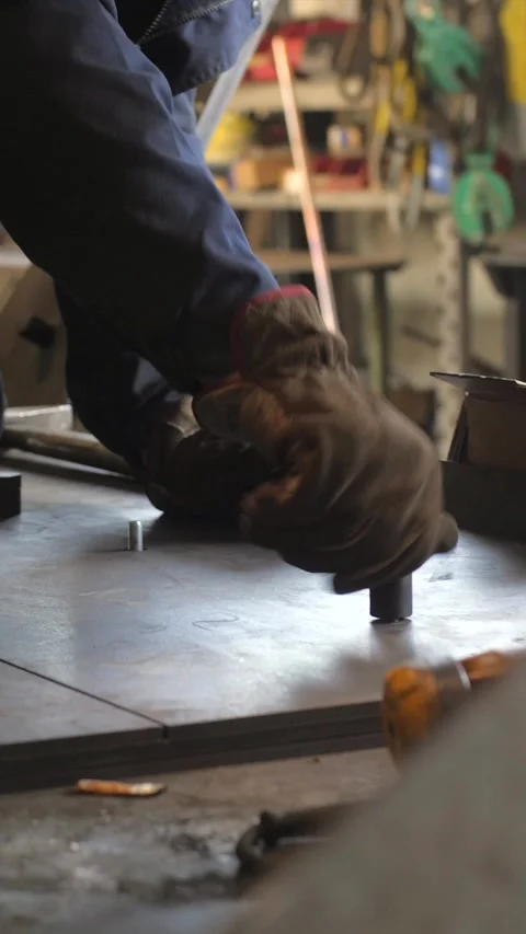 Construction worker screwing screw with hands in protective gloves, vertical Stockbeeldmateriaal 332815587