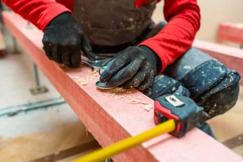 Construction worker screws bolts up tight on the stud on the wooden block in Stock Photos