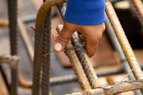 Construction worker securing steel bars with wire rod for reinforcement of ce Stock Photos