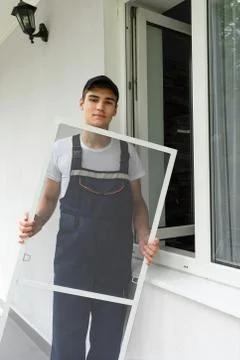 Construction worker sets mosquito net on a plastic windows Foto stock