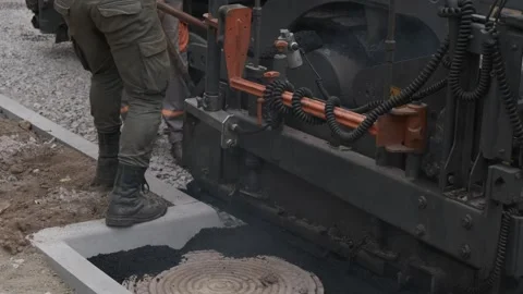 Construction worker shoveling fresh hot asphalt next to paving machine on s.. Stock Footage 339802542