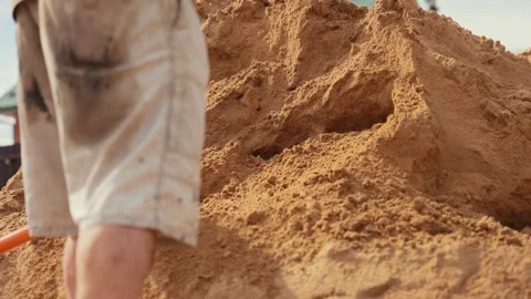 Construction worker shoveling a large pile of sand Stock Footage 341294857