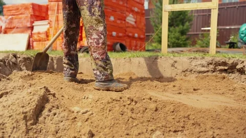 Construction worker shoveling sand in foundation trench Stock Footage 341294615
