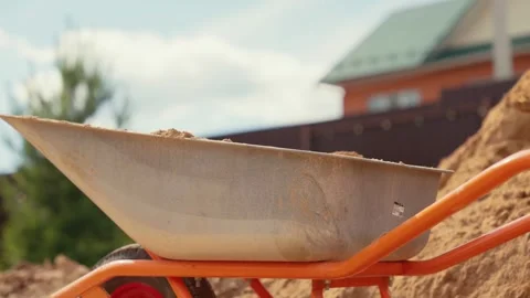 Construction worker shoveling sand into wheelbarrow Stock Footage 341294859
